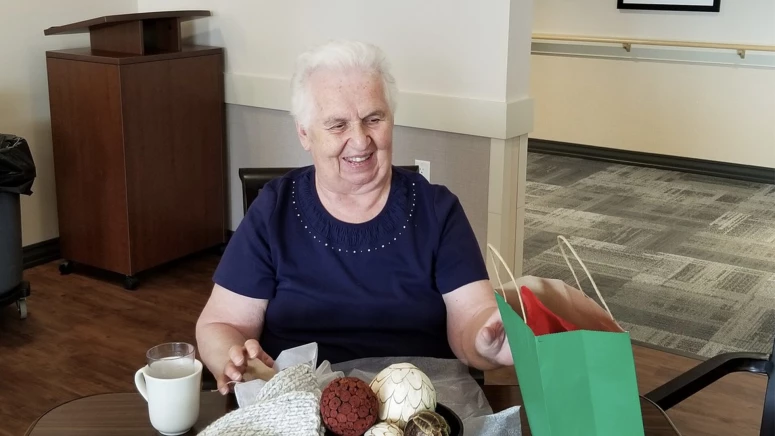 A senior citizen smiling while drinking coffee