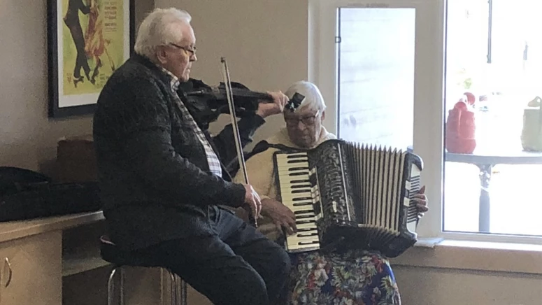 An elderly couple playing musical instruments